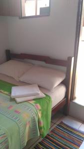 ピレノポリスにあるSuítes São Judasのベッド(白い枕、緑の毛布付)