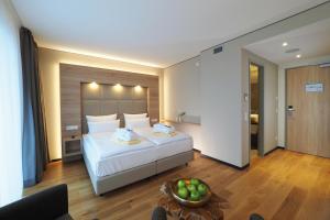 um quarto com uma grande cama branca e uma taça de fruta em WONNEMAR Resort-Hotel em Wismar
