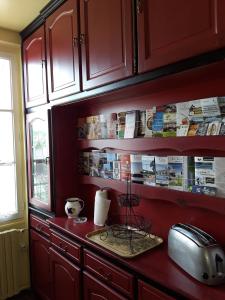 une cuisine avec des placards rouges et un comptoir avec un grille-pain dans l'établissement Le Repos du Marinier, à Gien