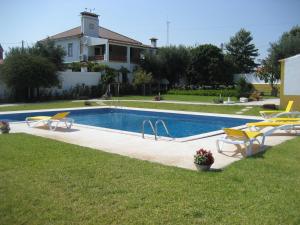 a swimming pool with yellow chairs and a house at A Tejada in Ortiga