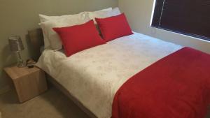 a red and white bed with red pillows in a bedroom at Hermanus Beach Club 144 in Hermanus