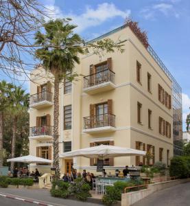 um edifício com pessoas sentadas fora dele em The Rothschild Hotel - Tel Aviv's Finest em Tel Aviv
