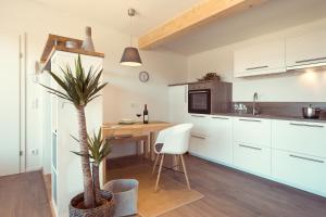 a kitchen with white cabinets and a table with a palm tree at Simply Home Apartments in Ueberackern
