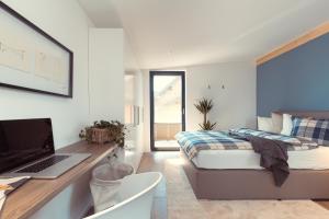 a bedroom with a bed and a desk with a laptop at Simply Home Apartments in Ueberackern