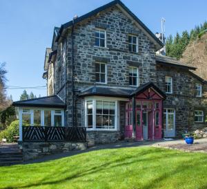 a stone house with pink doors and a yard at Summerhill Guest House in Betws-y-coed