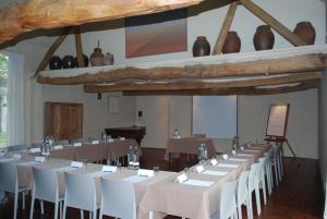 Opglabbeek的住宿－Orshof，一间设有一排桌子和白色椅子的房间