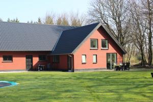 uma casa vermelha com um telhado preto em Skovgårdens Apartment em Grindsted