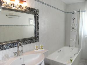 a bathroom with a tub and a sink and a mirror at Hotel Rural Can Maries in Puerto de San Miguel