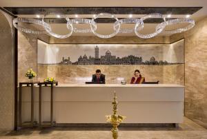 a lobby with two people sitting at a reception desk at The Baroda Residency in Vadodara