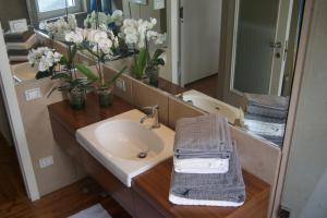 bagno con lavandino, specchio e fiori di Riva Celeste a Riva del Garda