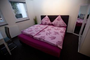 ein Schlafzimmer mit einem rosa Bett mit Kissen darauf in der Unterkunft Petite Paris in Bad Wildungen