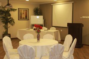 a conference room with a table and chairs and a screen at فندق ضيافة القرية Al Diyafa Hotel in Al Ahsa