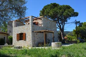 uma casa de pedra com uma árvore ao fundo em Pyrgos Luxury Country Home em Ialyssos