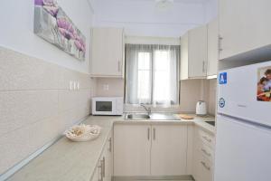 a white kitchen with a sink and a microwave at Villa Repas in Pefkochori
