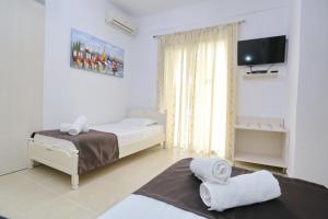 a white bedroom with a bed and a tv at Villa Repas in Pefkochori