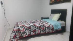 a bedroom with a bed with a quilt on it at Apartaestudios El Cable in Manizales