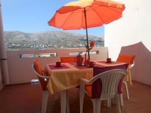 a table with an orange umbrella on a balcony at Donami Apartments in Pag