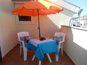 a table and chairs with an umbrella on a balcony at Donami Apartments in Pag