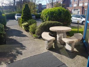 une table en pierre et deux bancs sur un trottoir dans l'établissement Hôtel du stade ex Kyriad Direct Lille Est Stade Pierre Mauroy, à Villeneuve d'Ascq