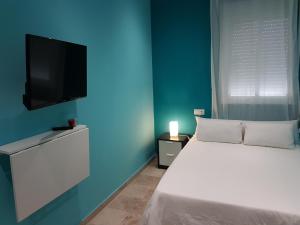 um quarto com uma cama e uma televisão de ecrã plano em Vivienda Reina Victoria em Huelva