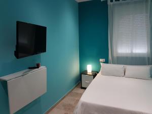 Un dormitorio con una cama y un televisor de pantalla plana. en Vivienda Reina Victoria, en Huelva