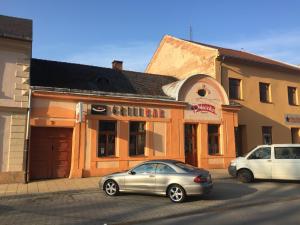 due auto parcheggiate di fronte a un edificio di Grillbar Penzion & Restaurant a Spišská Nová Ves