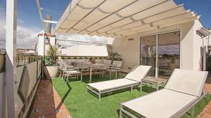 un patio con sillas blancas y una mesa en Beach Penthouse, en Sitges