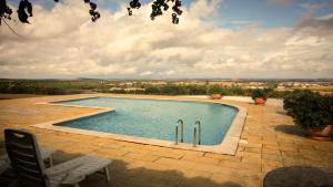a swimming pool on a brick patio with a view at Monte do Ravasco Country House in Estremoz