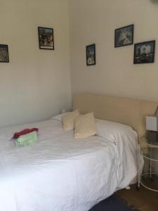 リヴォルノにあるDa Lindaの白いベッド1台、壁に4枚の写真が飾られたベッドルーム1室