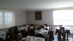 a dining room with tables and chairs and a window at Hotel El Millón in Viveiro