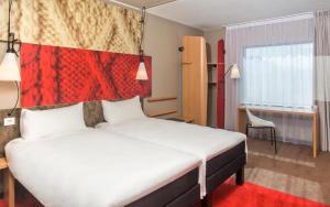 a bedroom with a large bed with a red headboard at ibis London Greenwich in London