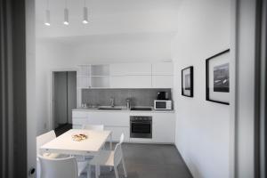 a white kitchen with a white table and chairs at Le Ancore Luxury Apartments in Favignana