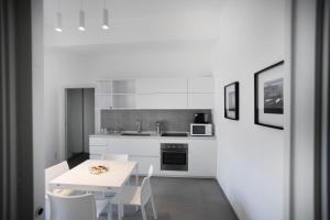 una cucina bianca con tavolo e sedie bianchi di Le Ancore Luxury Apartments a Favignana