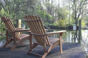 two rocking chairs sitting on a dock near the water at Crafts Hill Barn in Cambridge