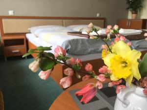 a vase with flowers on a table next to a bed at Apartmán Darmon in Piešťany