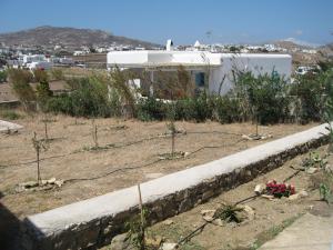 a garden with trees and a building in the background at Myconian Cottage in Ano Mera