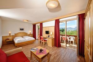 a hotel room with a bed and a desk with a table at Hotel St. Justina Hof in Appiano sulla Strada del Vino