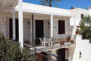 Cette maison blanche dispose d'un balcon avec une table et des chaises. dans l'établissement Appartamenti Monacò, à San Vito Lo Capo