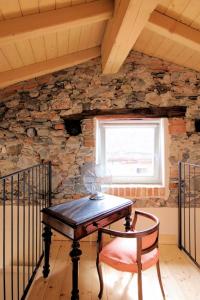 uma mesa e uma cadeira num quarto com uma parede de pedra em Guest House Al Castello em Gravedona