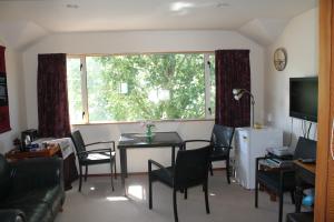 sala de estar con mesa, sillas y ventana en Aroha Riccarton Bed and Breakfast, en Christchurch