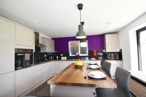 cocina con mesa de madera y paredes púrpuras en Gorse House en Leicester