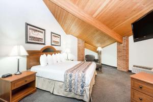 ein Hotelzimmer mit einem Bett und einem Flachbild-TV in der Unterkunft Baymont by Wyndham LeMars in Le Mars