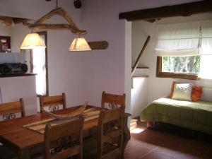 a dining room with a table and chairs and a bed at Cabañas La Curucucha in Nono