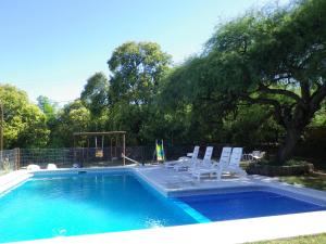 a swimming pool with two chairs and a tree at Cabañas La Curucucha in Nono
