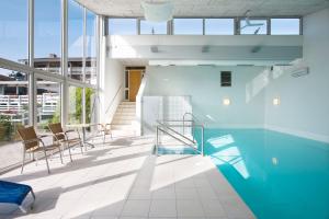 a swimming pool in a building with chairs and windows at Hotel Friheden in Allinge