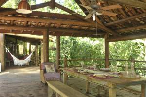 a wooden deck with a table and a ceiling fan at Casa Sertão de Camburi in Camburi