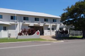 Biały budynek z czerwonym znakiem przed nim w obiekcie Castle Crest Motel w mieście Townsville