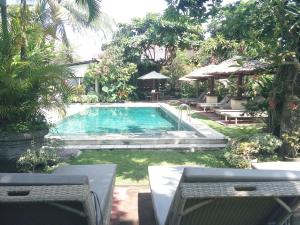 una piscina en un patio con mesas y sillas en Gazebo Beach Hotel, en Sanur