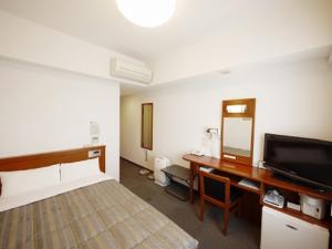 a hotel room with a bed, desk and television at Hotel Route-Inn Mojiko in Kitakyushu