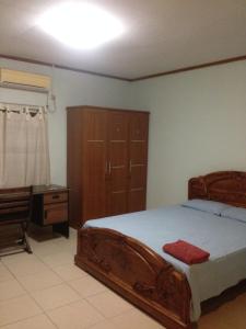 a bedroom with a large wooden bed and a desk at Vila Bemori in Dili
